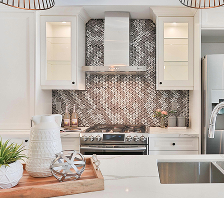 Modern white kitchen featuring a stylish ceramic backsplash with intricate patterns, white cabinetry, and stainless steel appliances.