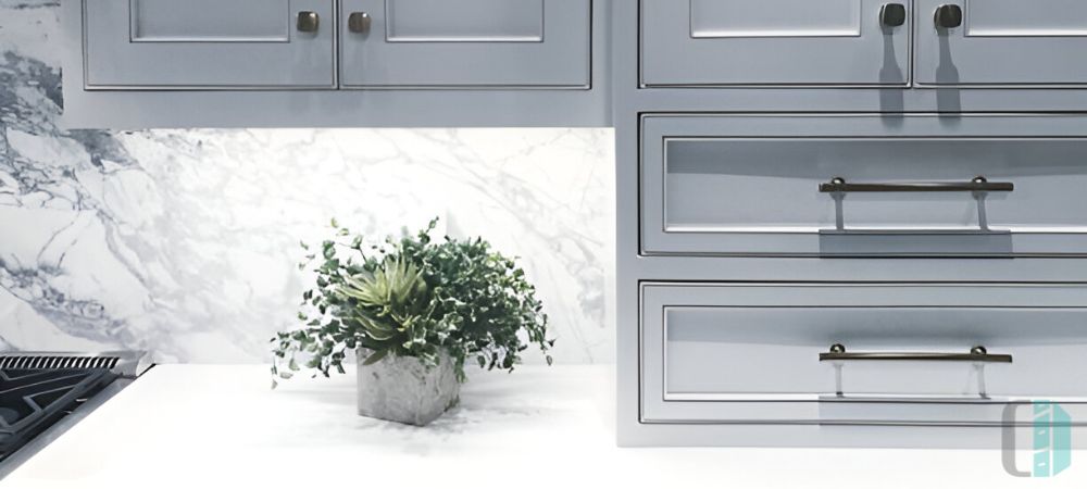 A modern kitchen with gray cabinets and a single slab marble backsplash 