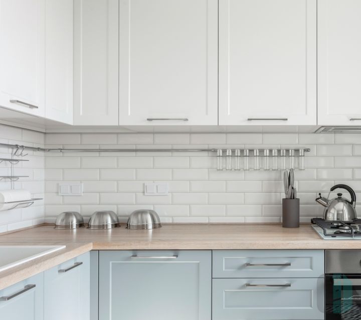 A modern kitchen with light gray cabinets and a classic subway tile backsplash