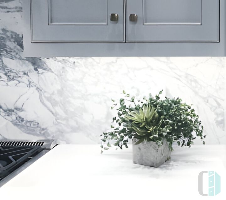 A modern kitchen with gray cabinets and a single slab marble backsplash 